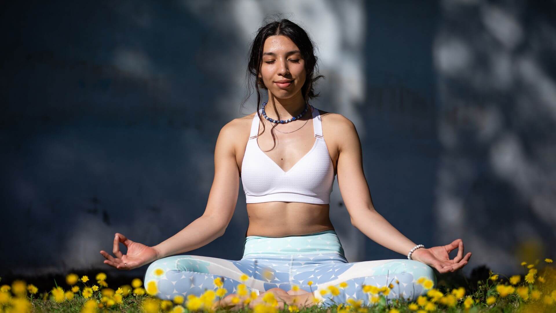 woman in yoga clothes meditating among flowers