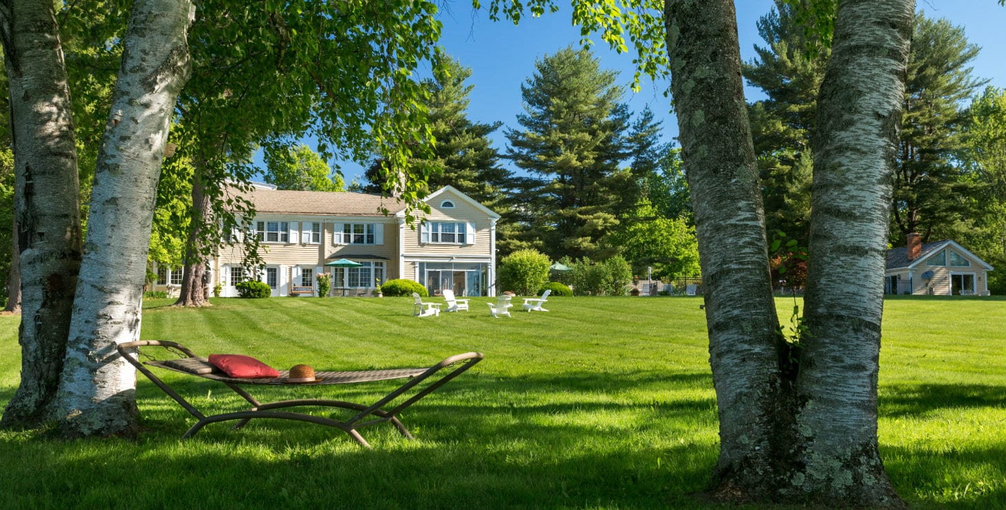 Front view of the inn with rich green grass and a red hammock