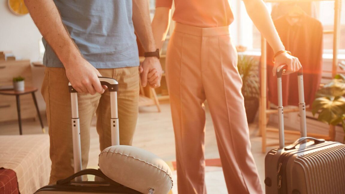 couple holding hands, and holding suitcases to go on vacation