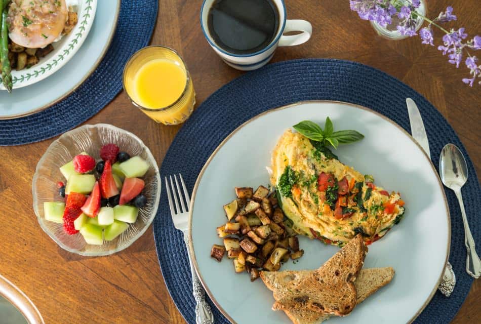 Close up view of breakfast dish with omelette, wheat toast, and fried potatoes