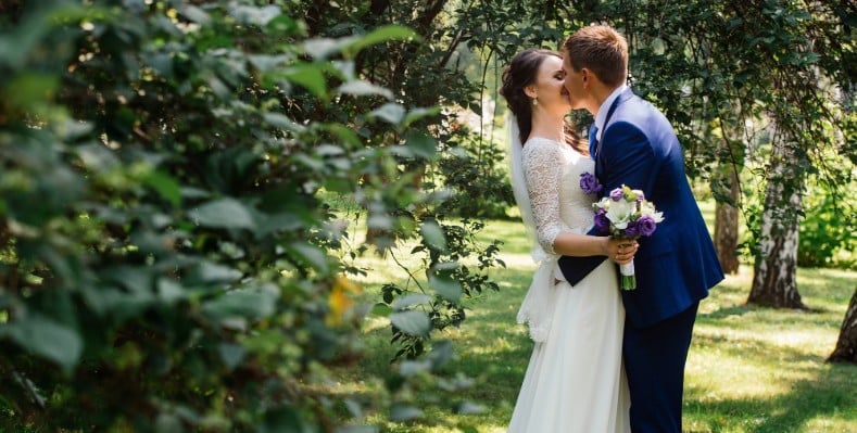 Happy bride and groom kissing outside