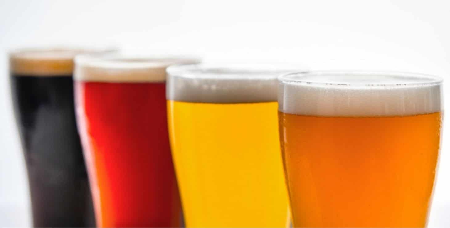 4 beer glasses filled with different colored beer: dark, reddish brown, gold and amber