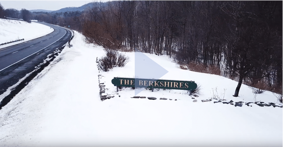 Overview of winding road surrounded by snow ith a green sign that says The Berkshires