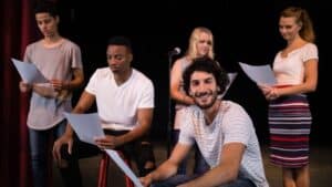 group of actors reading scripts on stage