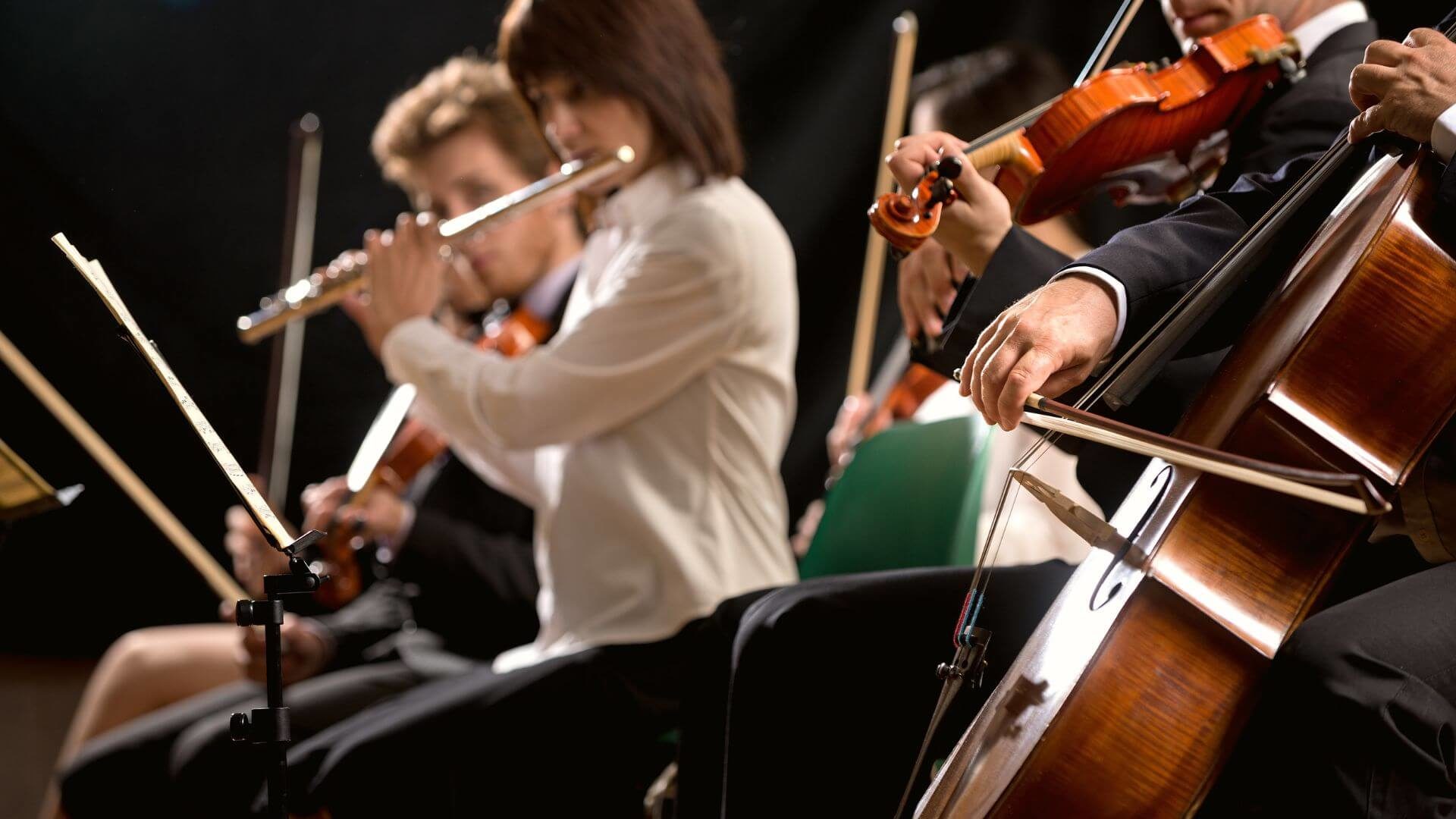 Performers playing various musical instruments during symphony presentation.