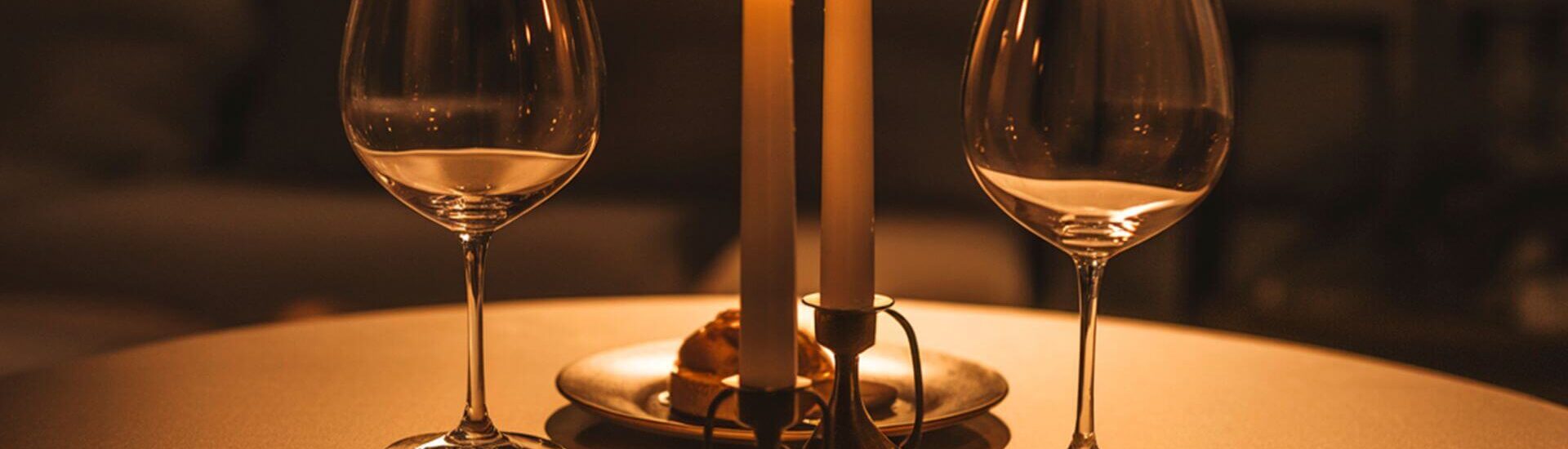 candle lit table with two wine glasses and burning candles creating a romantic dinner setting