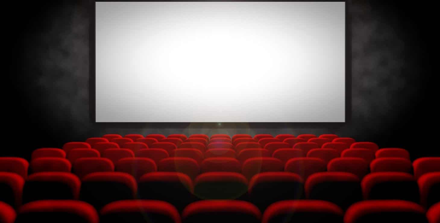 Rows of red velvet seats facing a large theater screen