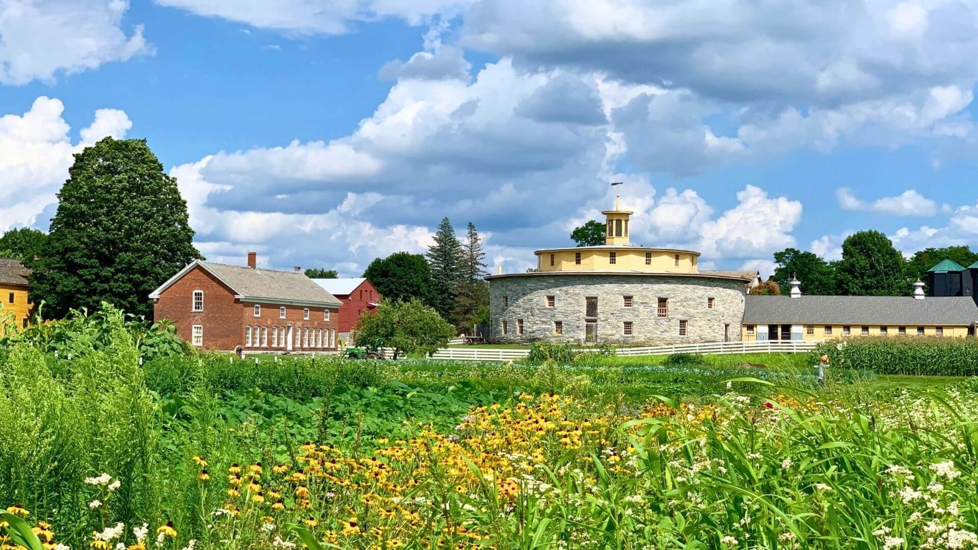 The Round Stone Barn at Hancock Shaker Village is surrounded by wildflowers and farmland in the Berkshires.