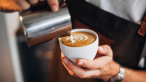 A person is handcrafting a latte