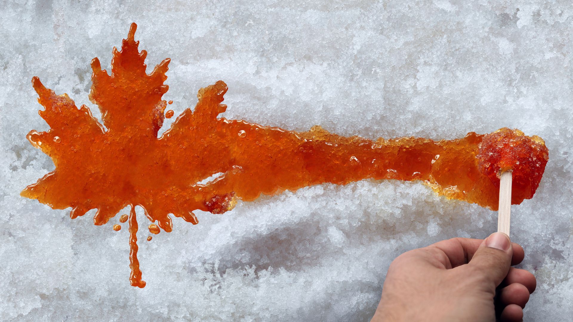 Maple candy being rolled on a stick over snow