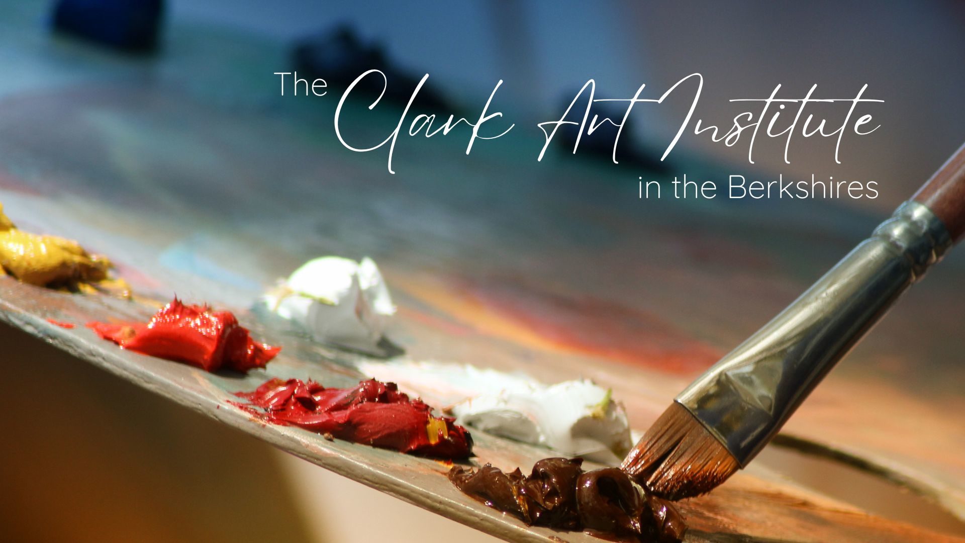 A paint brush dipping into the paint on a painter’s palette with text overlay “The Clark Art Institute in the Berkshires”