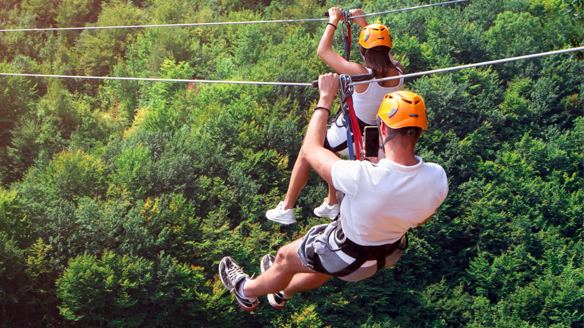Two people riding on a zipline