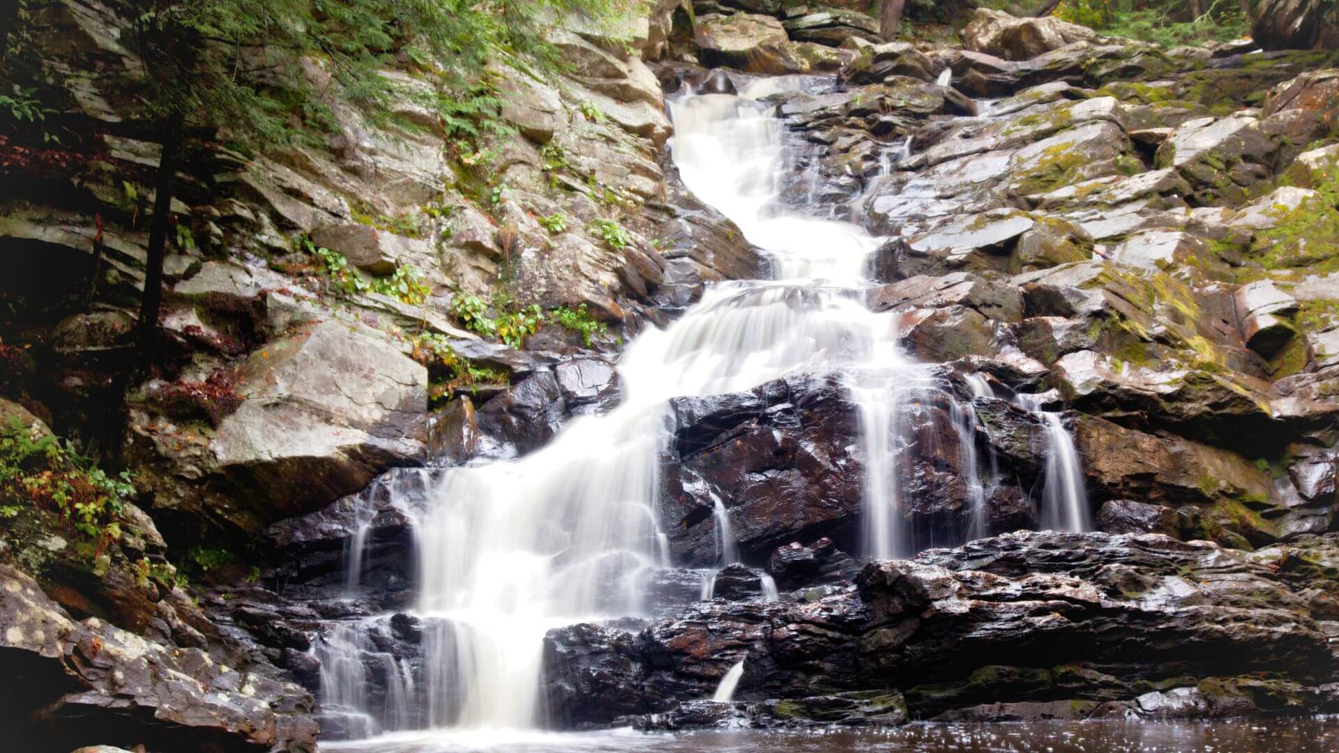 The multi-tiered Wahconah Falls cascading over large rocks in a wooded setting