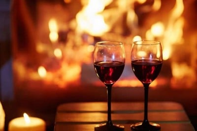 two red wine glasses in front of the fire