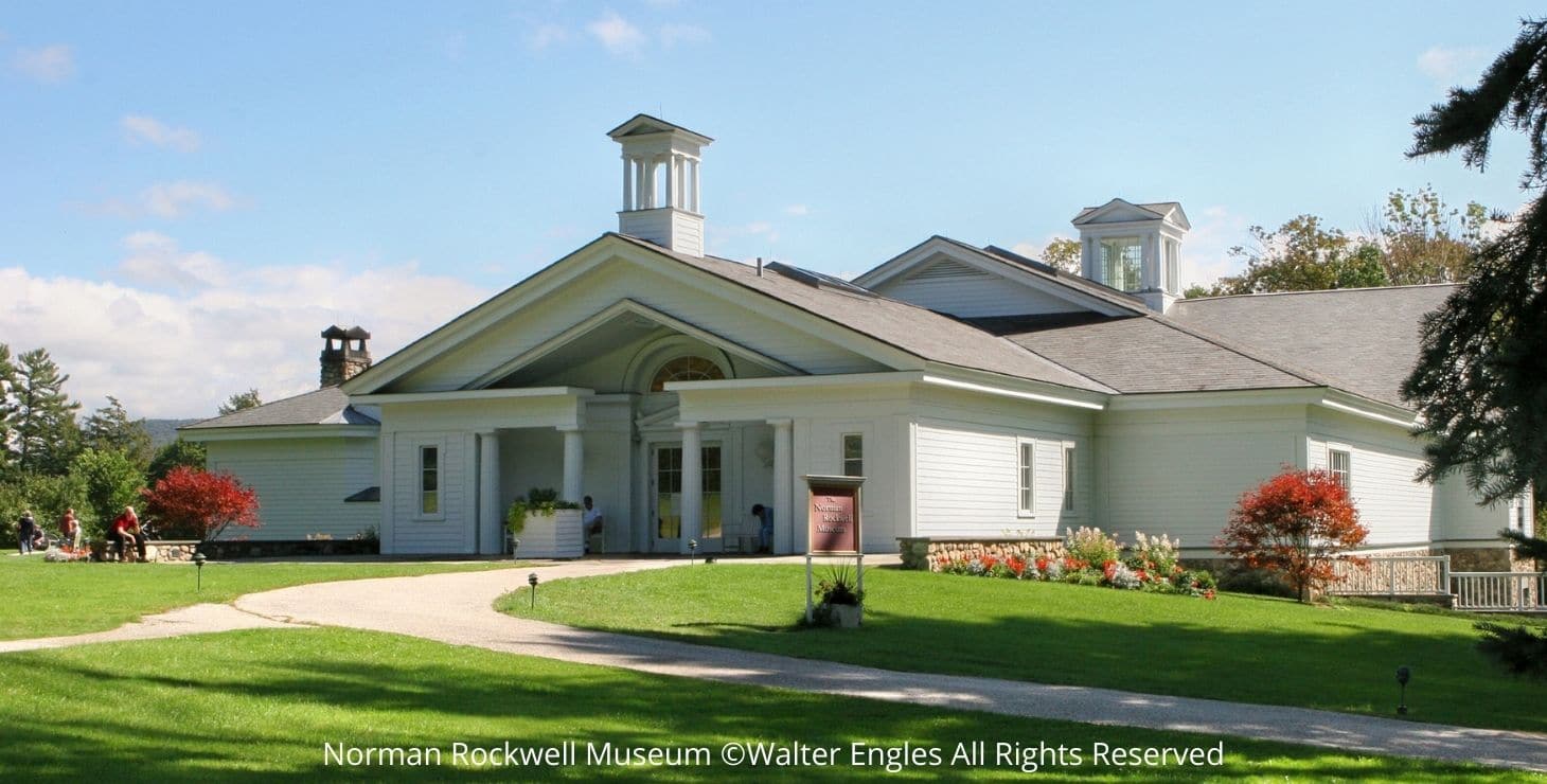 Exterior view of Norman Rockwell Museum, white building with gabled roofs, cupolas, and expansive green lawn