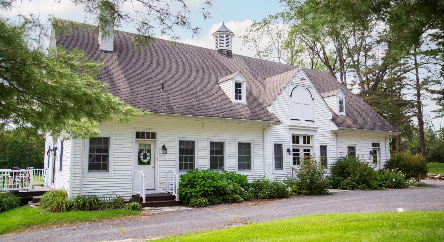 Exterior view of the Carriage House painted white and surrounded by green shrubs and trees