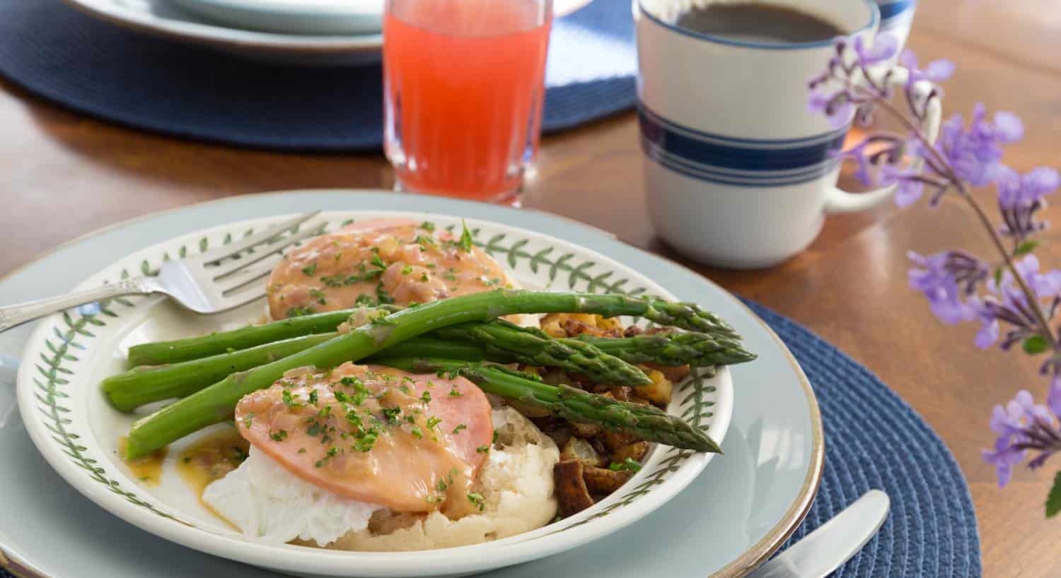 Close up view of breakfast dish with biscuits, eggs, ham, fried potatoes, and asparagus
