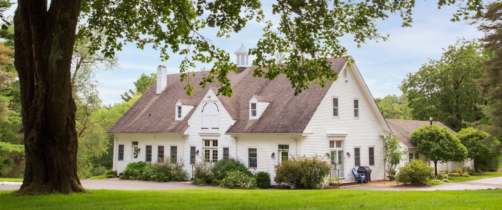 Exterior view of the Carriage House painted white and surrounded by green shrubs and trees