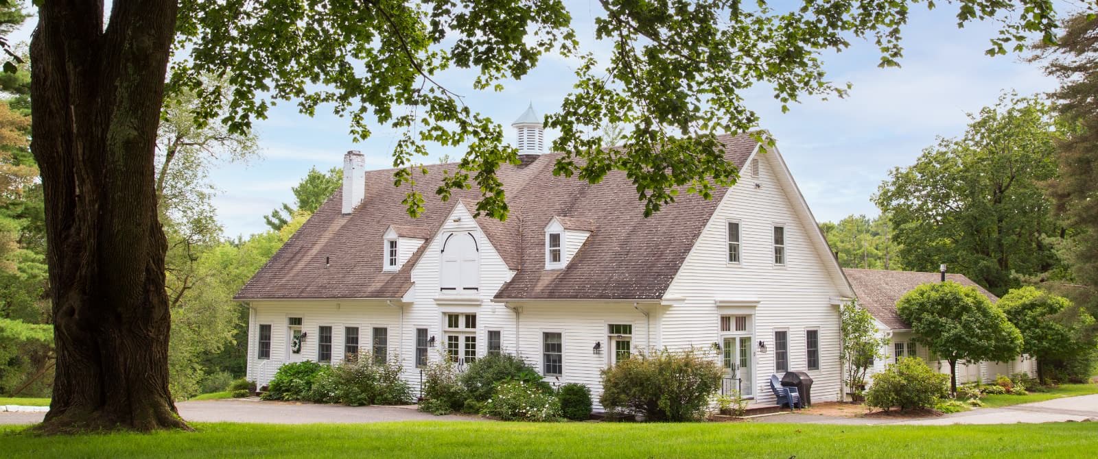 Exterior view of the Carriage House painted white and surrounded by green shrubs and trees