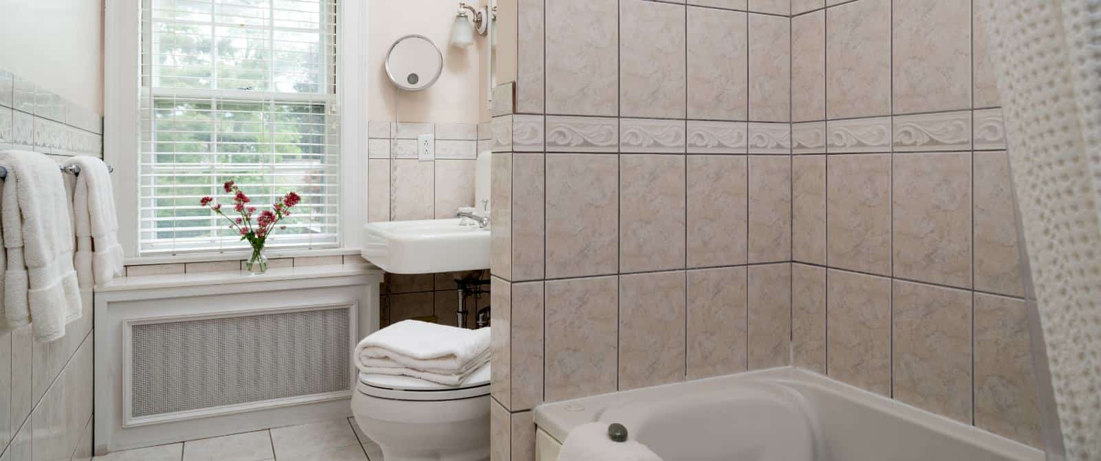 Bathroom with light colored tile, white sink, and white tub