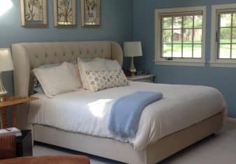 Bedroom with blue walls, white trim, upholstered headboard, white bedding, and multiple windows