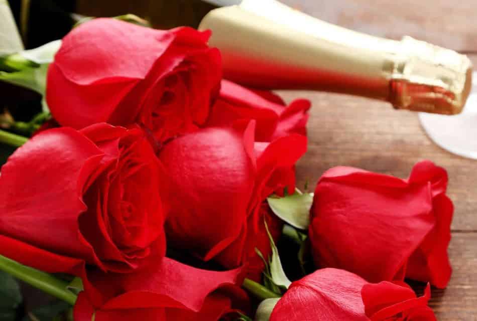 Close up view of a bouquet with red roses and bottle of wine