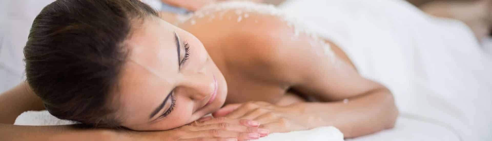 Close up view of woman laying on white table covered in white towel getting a spa treatment