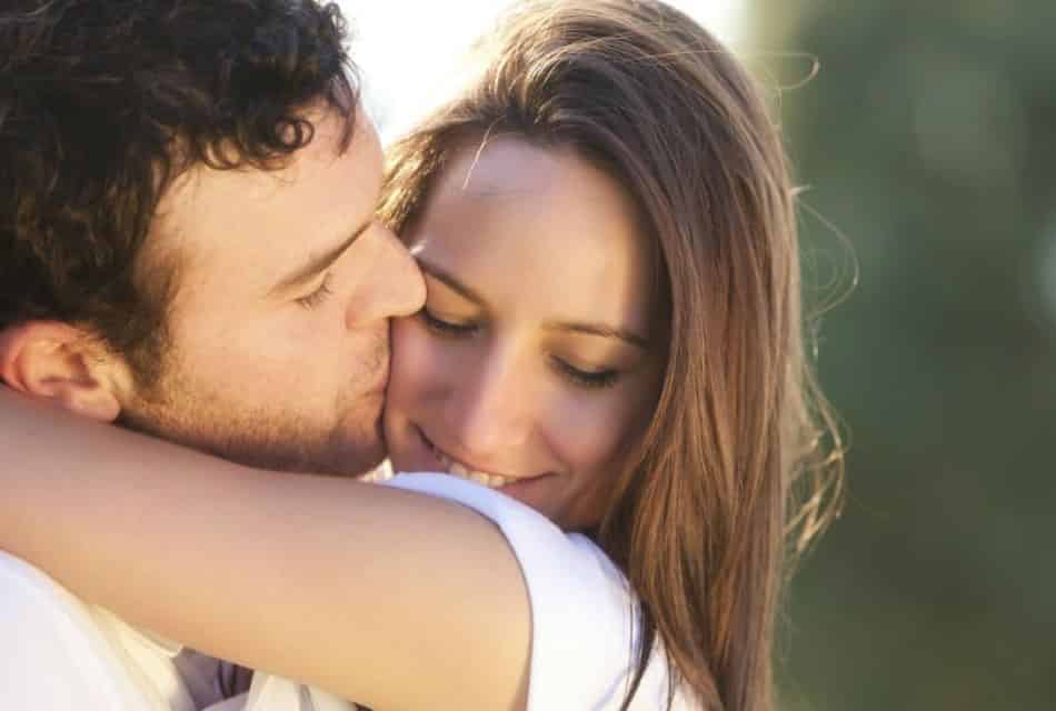 Close up view of woman hugging man who is kissing the woman on the cheek