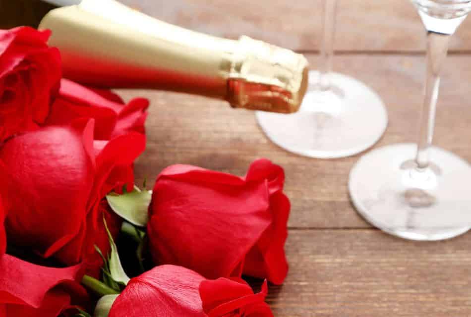 Close up view of a bouquet with red roses and bottle of wine