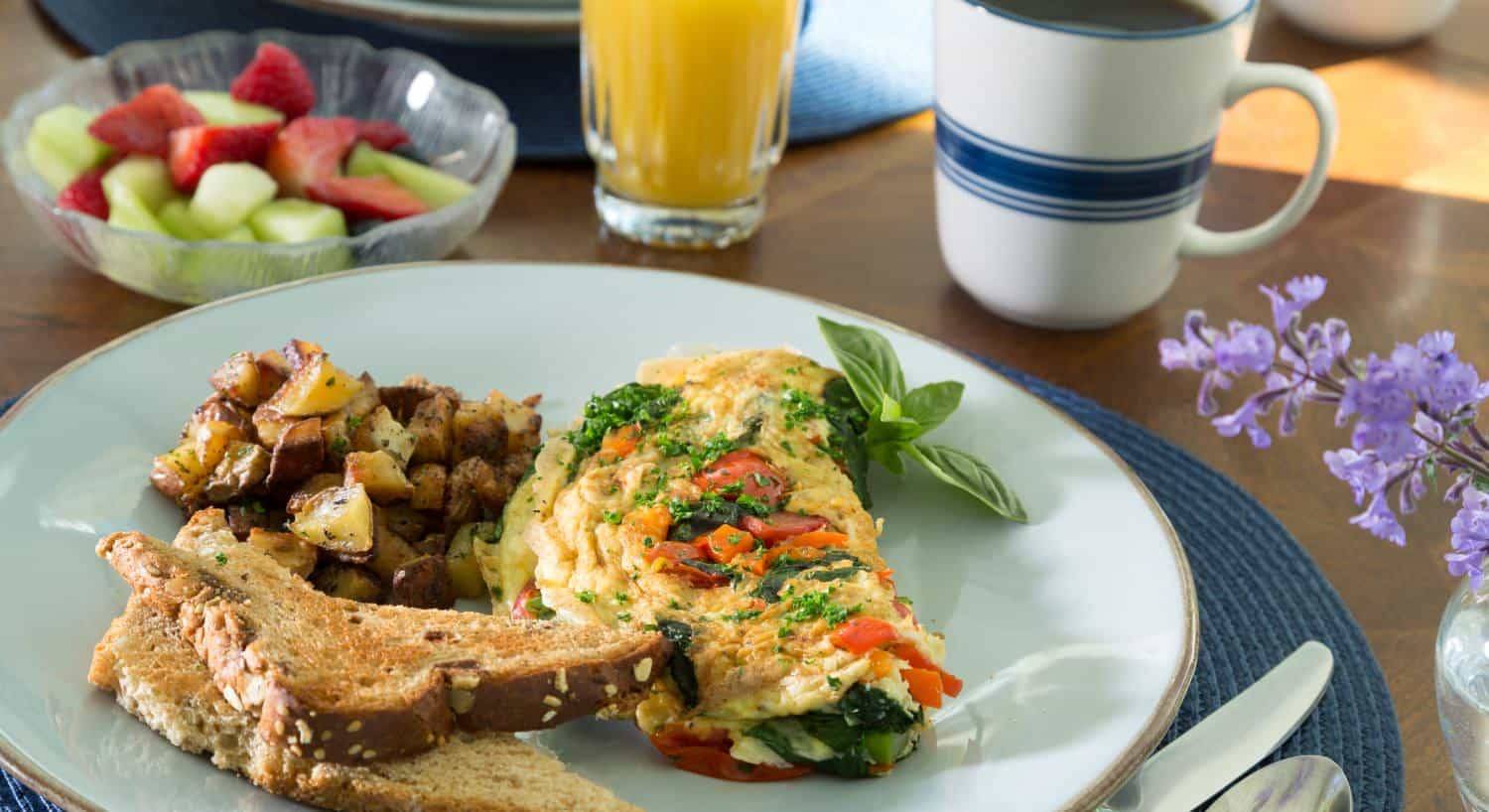 Close up view of breakfast dish with omelette, wheat toast, and fried potatoes