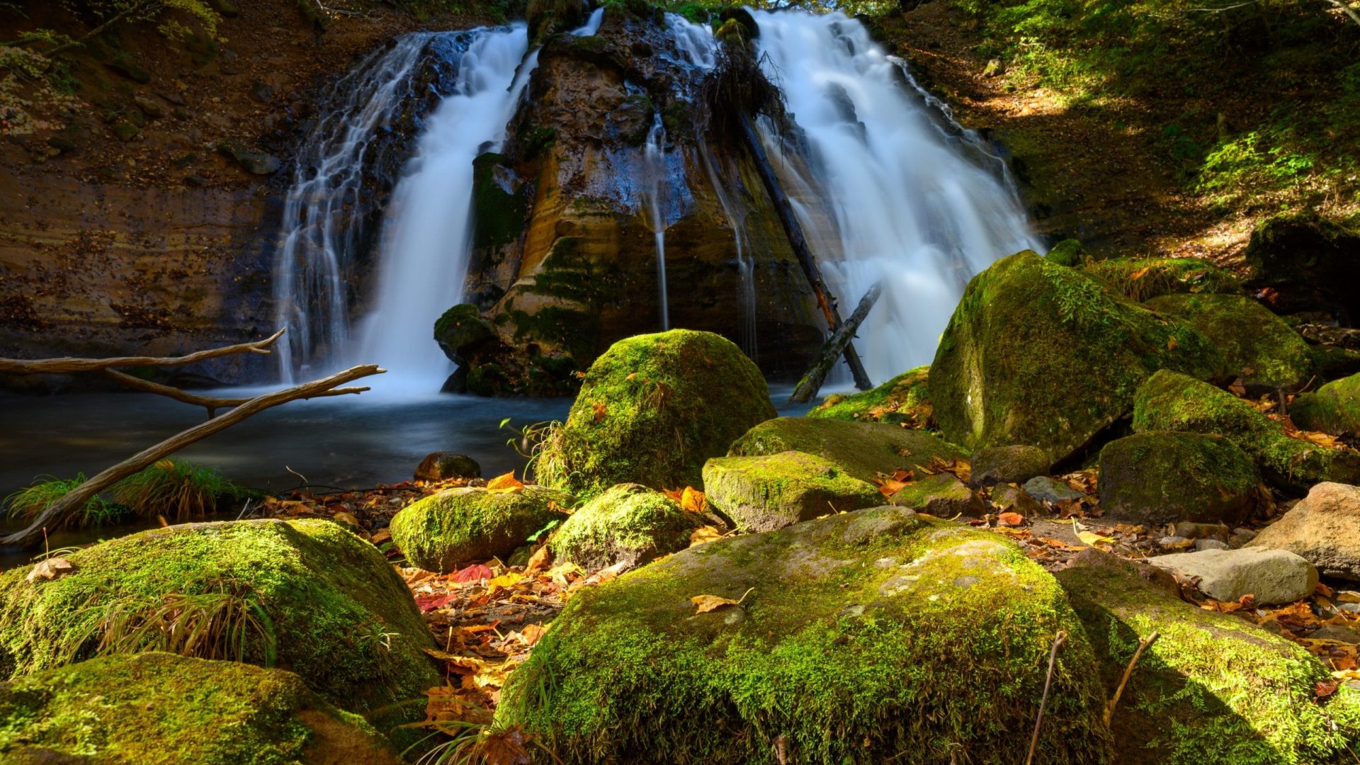 Waterfall cascading down rocks surrounded by mossy green rocks and trees